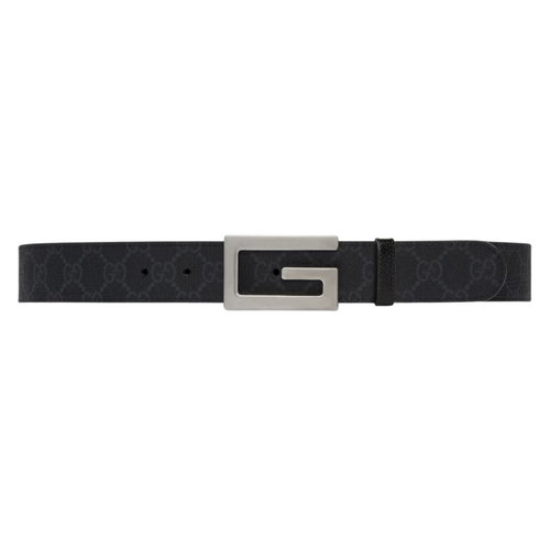 Black leather belt with large silver G-shaped buckle on jeans